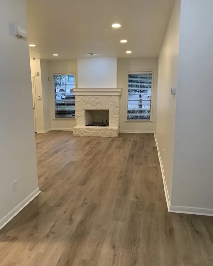 Living room with a restored stone fireplace and new flooring after water damage repair in Austin